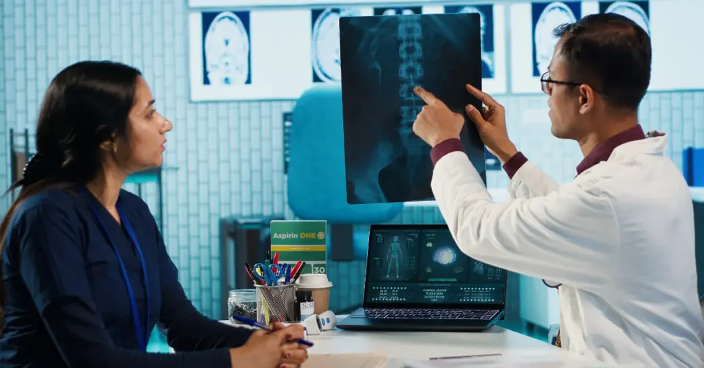 Orthopaedic oncosurgeon reviewing spine X-ray with patient for bone tumour diagnosis